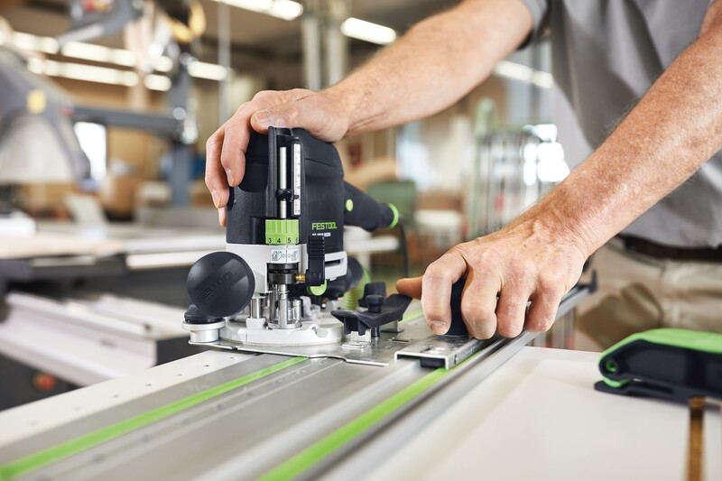 Person using a Festool router with woodworking accessories for precise drilling in a professional workshop setting