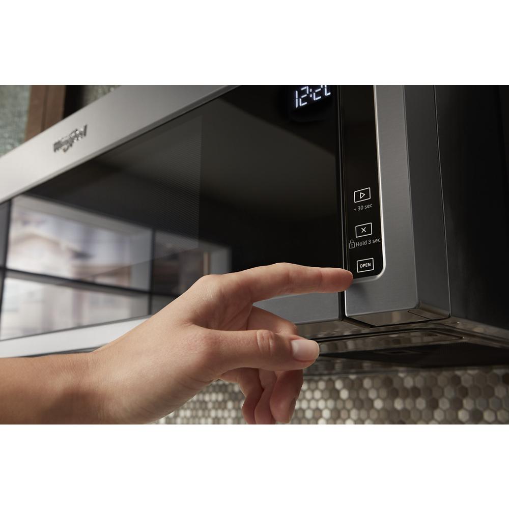 Hand pressing control button on black stainless steel microwave from over the range microwaves collection