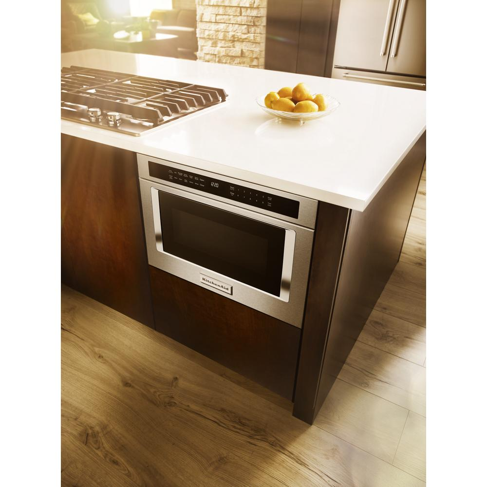 Built-in stainless steel microwave oven drawer installed under kitchen countertop next to gas cooktop with bowl of lemons on counter