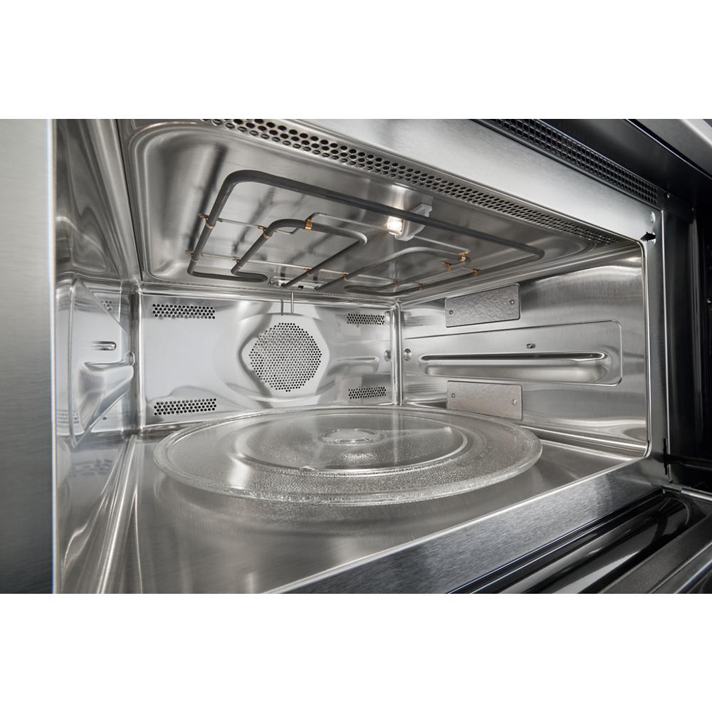 Interior view of stainless steel microwave oven cavity with glass turntable and heating element visible