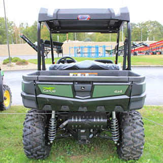 Rear view of a green John Deere utility vehicle with large off-road tires and visible suspension system