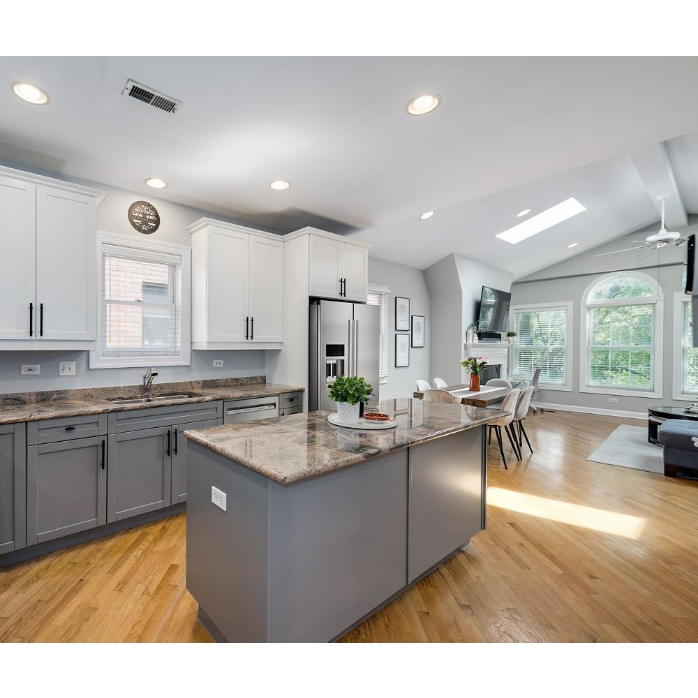 Bright open kitchen with two-tone cabinetry, granite counters, stainless steel appliances, and hardwood flooring in home improvement setting