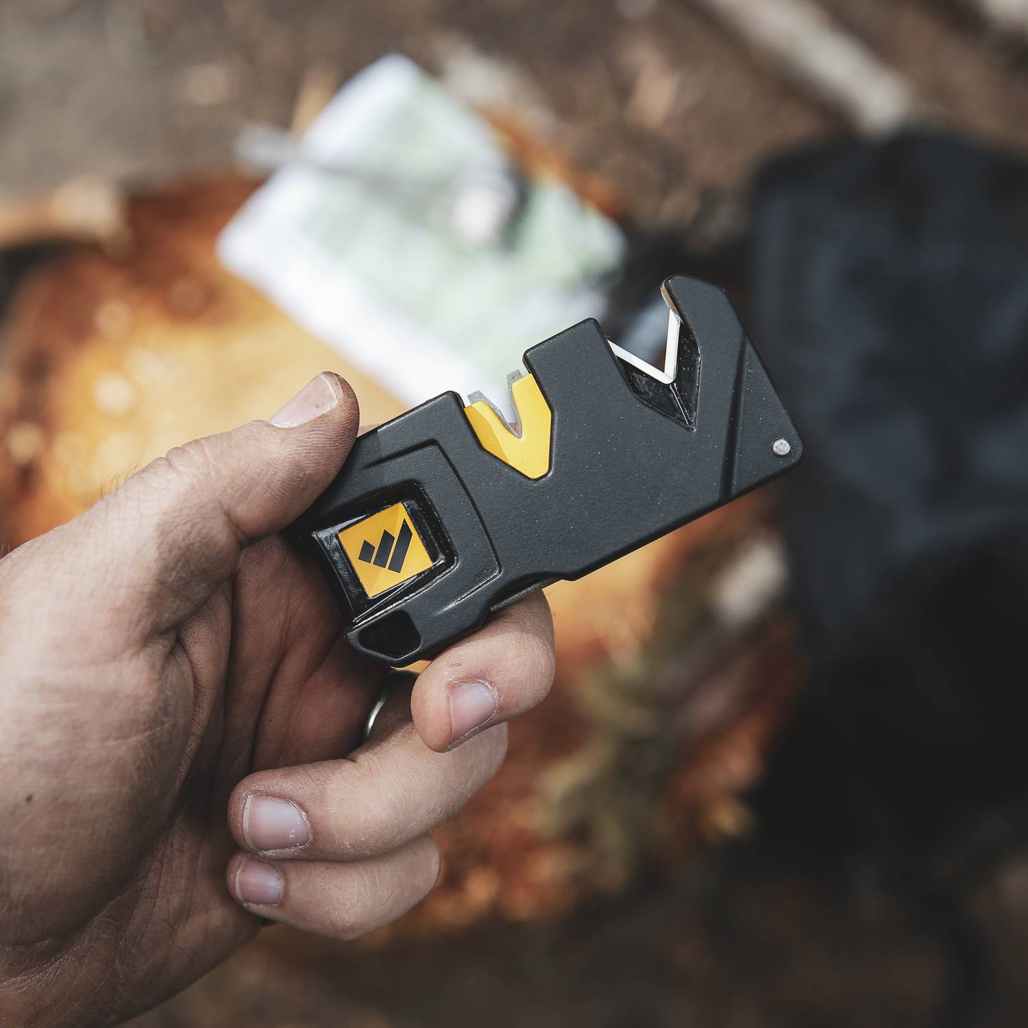 Hand holding compact black and yellow knife sharpener with dual sharpening slots for kitchen and woodworking tools