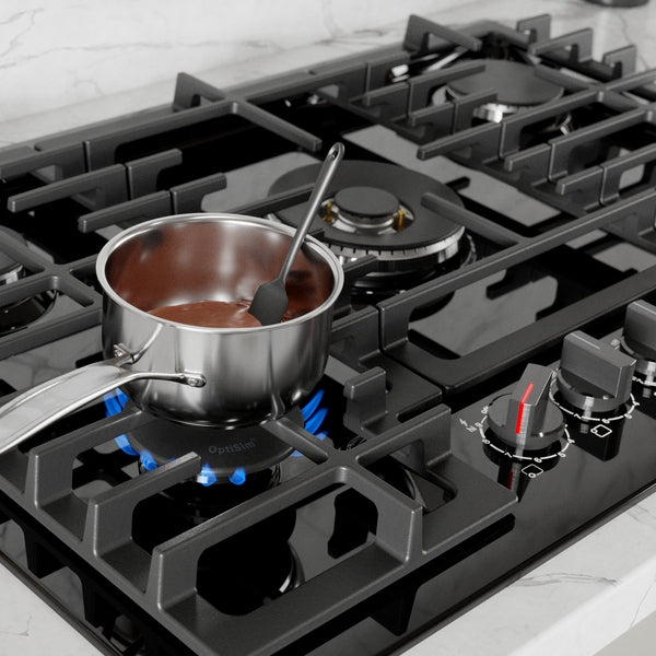 Black gas cooktop with stainless steel pot heating on blue flame, featuring control knobs and cast iron grates in modern kitchen setting