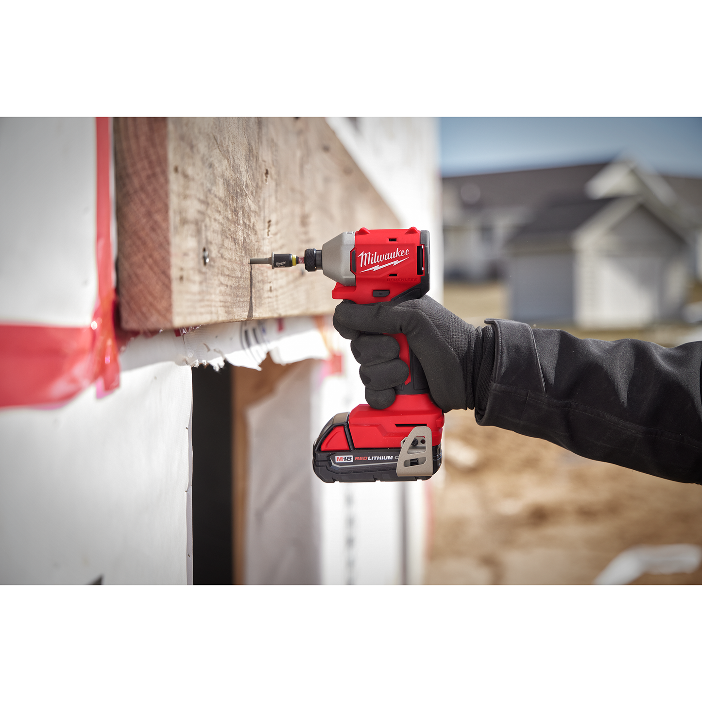 Red Milwaukee M18 compact brushless 1/4" hex impact driver being used for home improvement on wooden board
