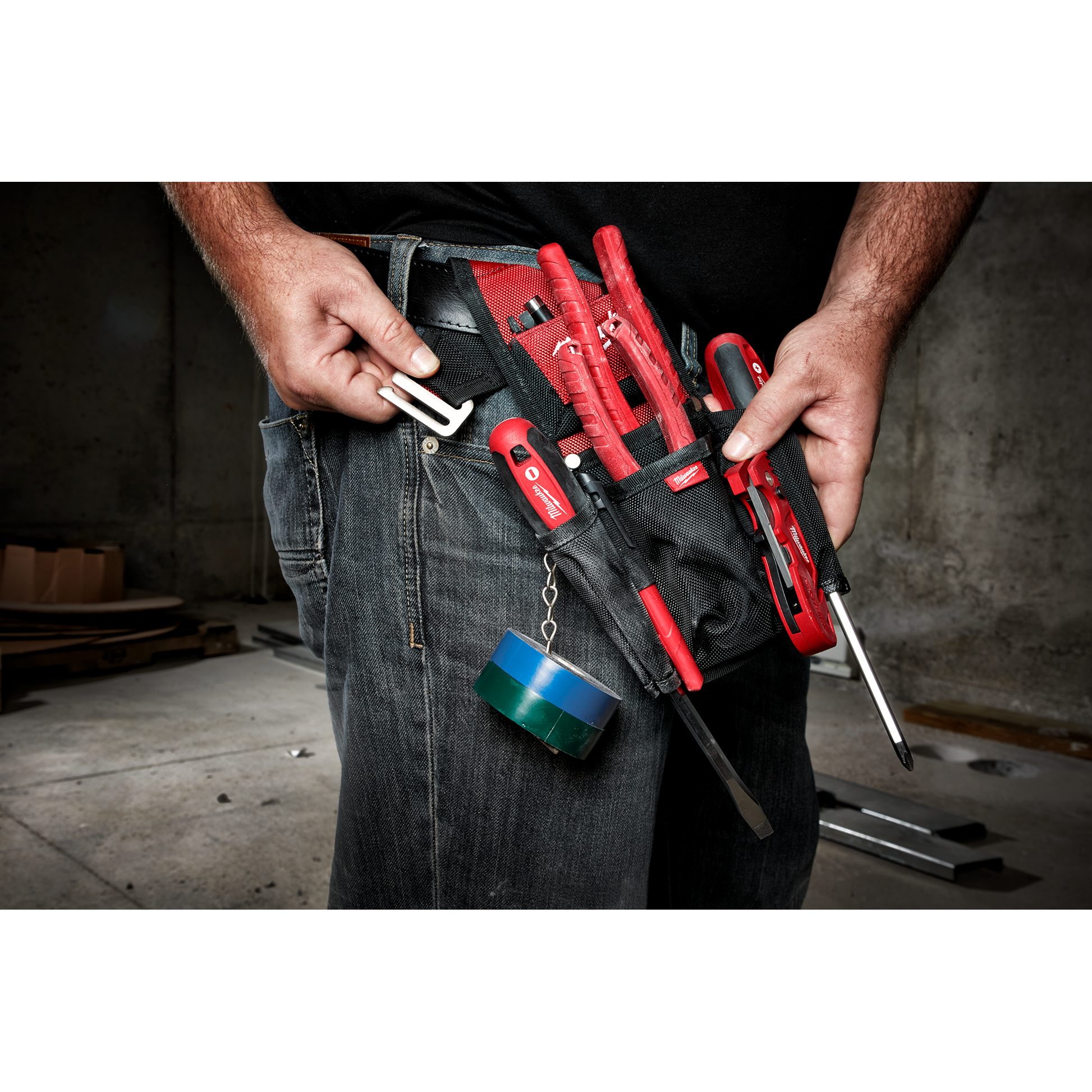Black and red compact utility pouch worn on belt holding hand tools and electrical tape for tools and home improvement use