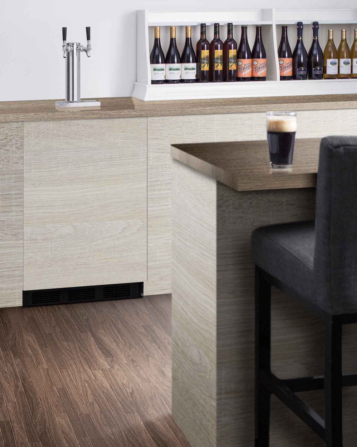 Built-in kegerator with dual taps integrated into modern light wood kitchen cabinetry and dark wood flooring