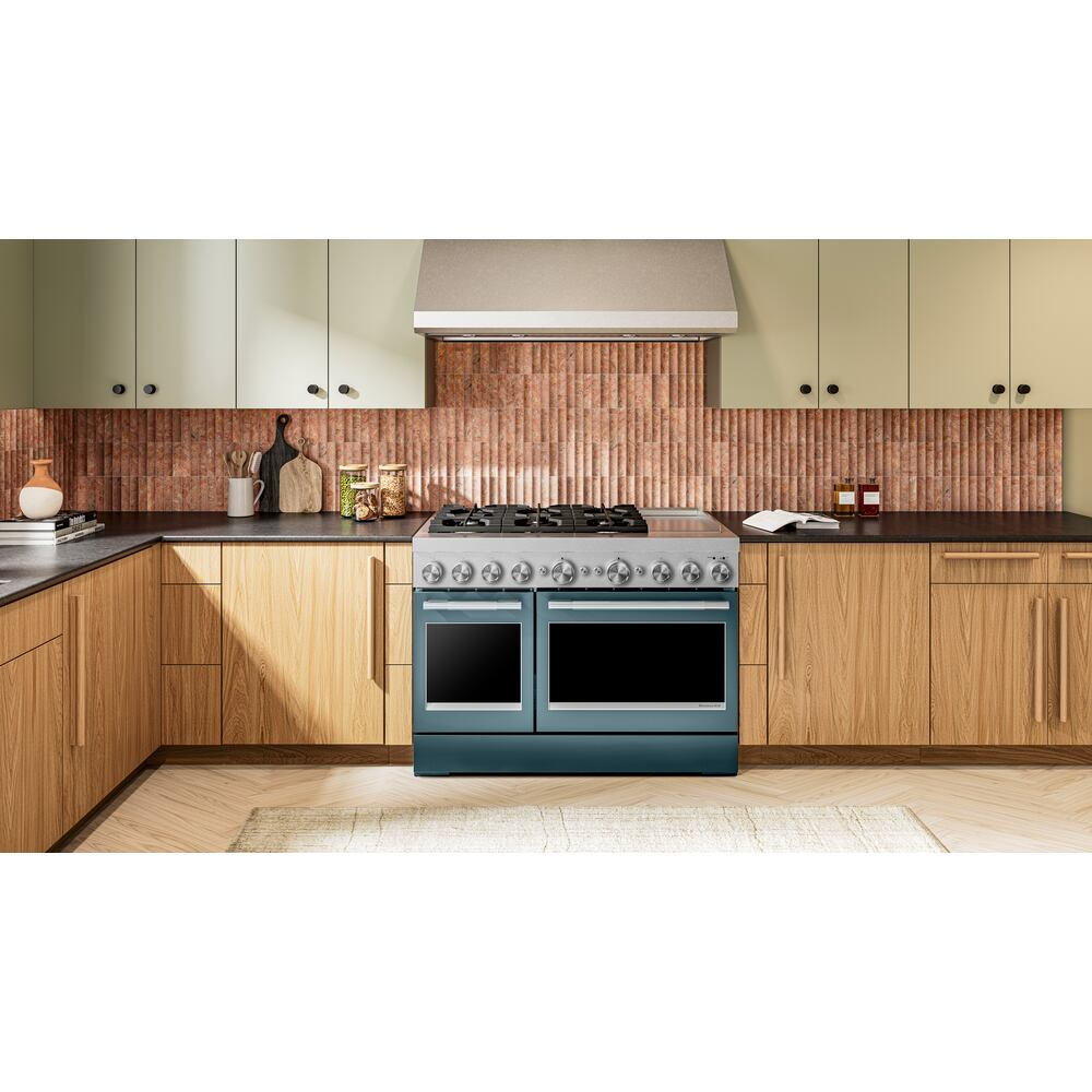 Sparkling blue dual fuel range with six burners and double ovens in modern kitchen with wood cabinets and copper tile backsplash