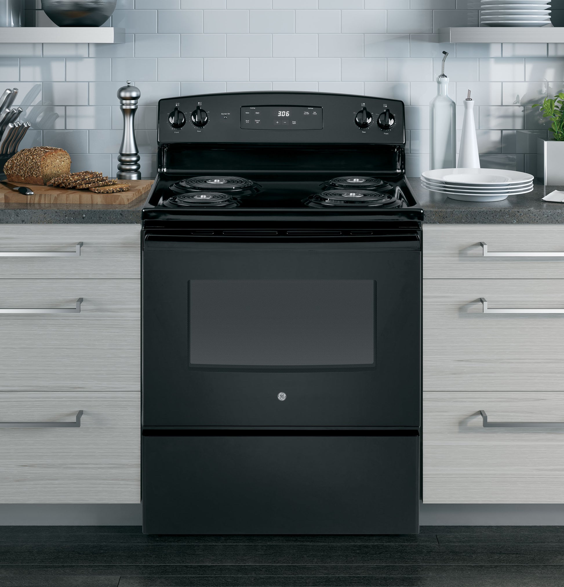 Black free-standing electric range with four coil burners in modern kitchen with gray cabinetry and subway tile backsplash