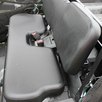 Black padded bench seat with seatbelt buckles inside a camo mid-size utility vehicle cabin
