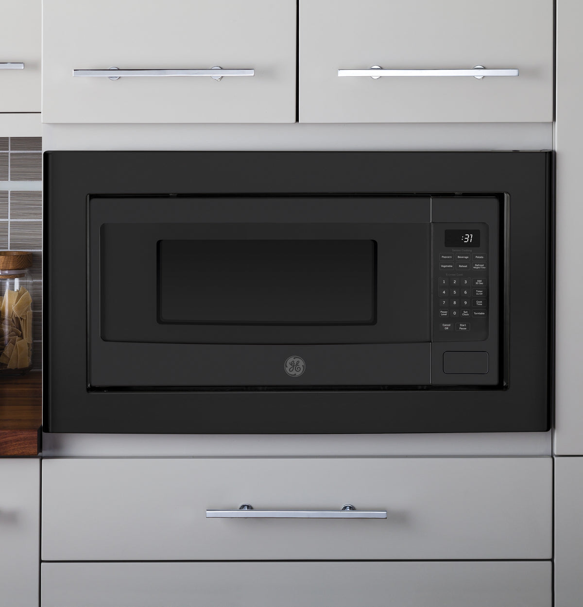 Black built-in trim kit surrounding a microwave installed in gray kitchen cabinetry in Appliances and Kitchen collections