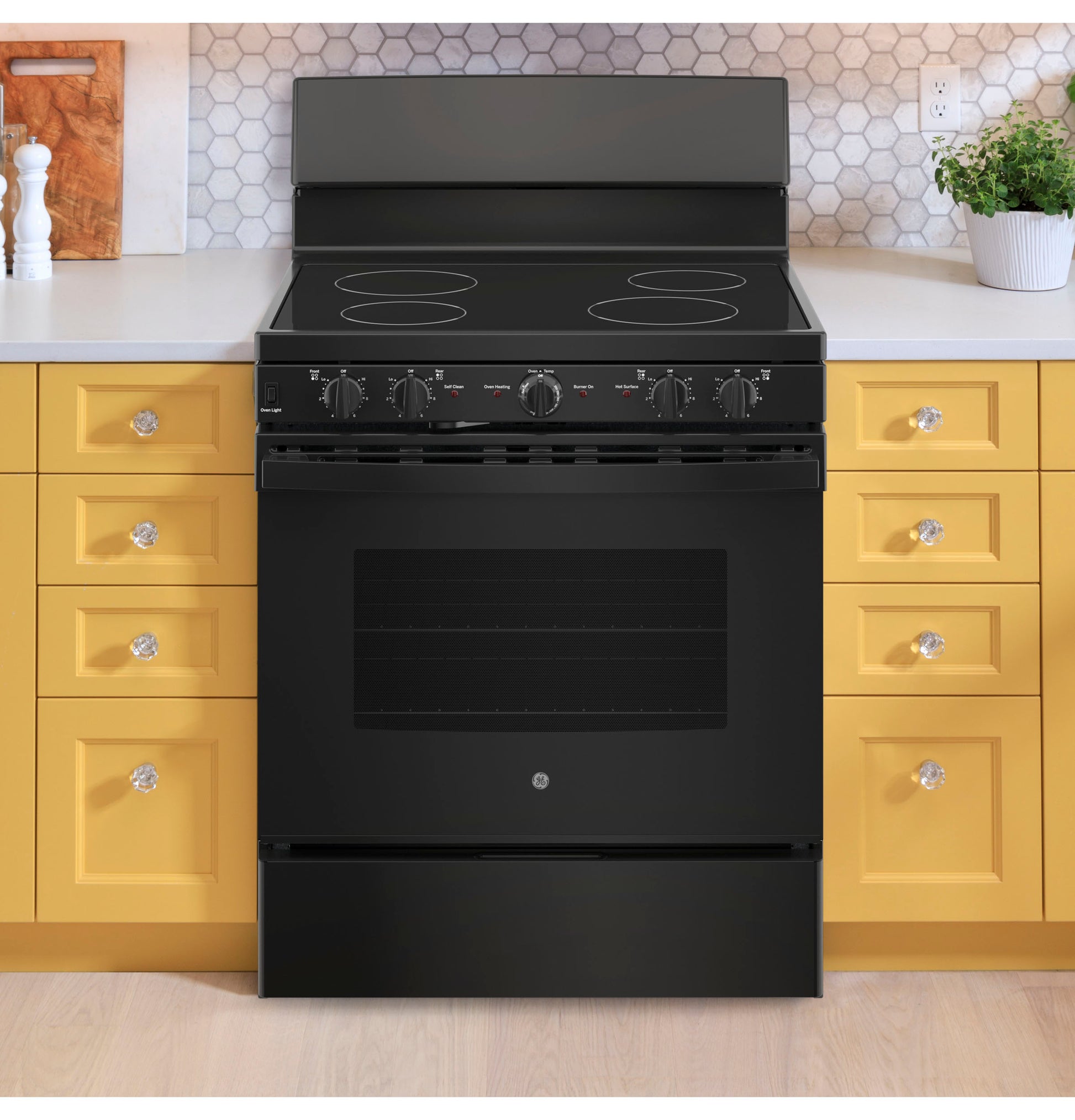 Black smooth electric cooktop range with control knobs in a modern kitchen featuring yellow cabinetry and white countertop