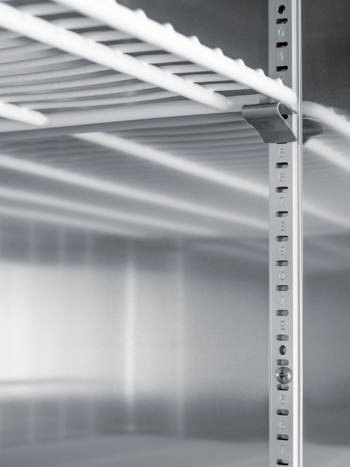Close-up of adjustable white wire shelf and numbered stainless steel interior in a commercial freezer from kitchen appliances collection