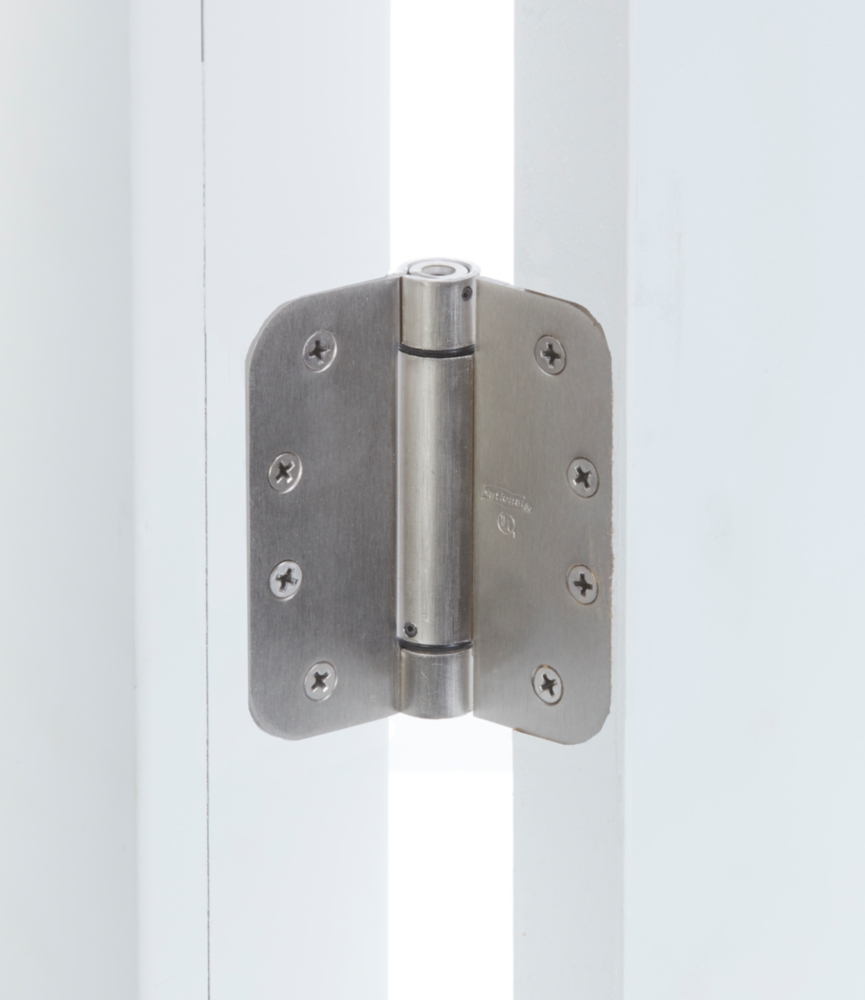 Satin nickel spring door hinge with 5/8-inch rounded corners installed on white door frame for home improvement tasks