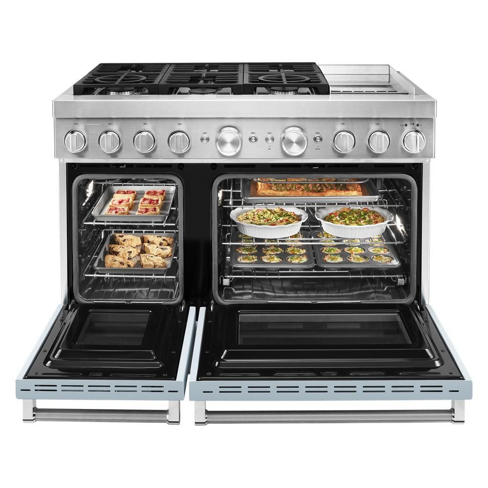 Commercial-style dual fuel range with griddle, six gas burners, and electric double oven filled with cooked dishes