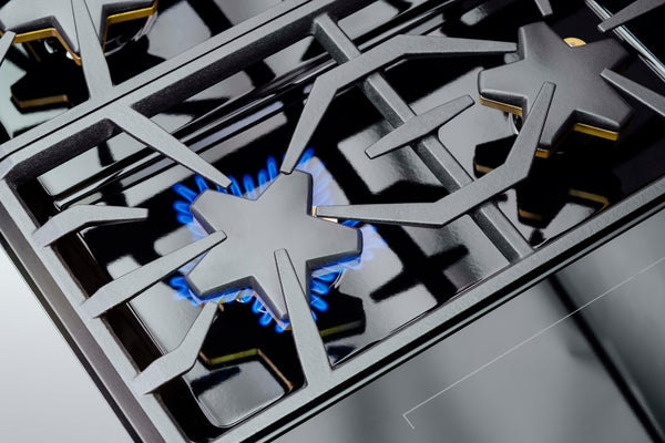 Close-up of a stainless steel gas burner with blue flame on a professional range in kitchen appliances collection