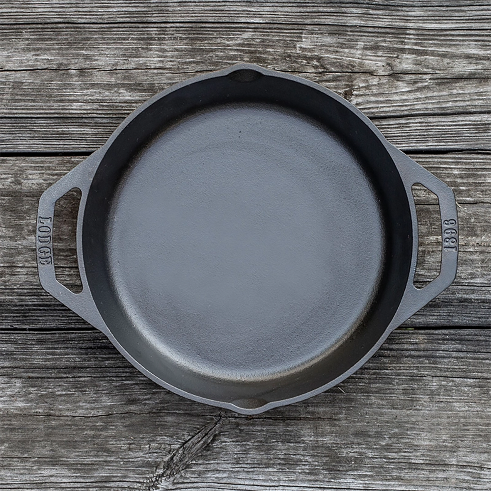 Black cast iron round pan with short side handles on rustic wooden surface in kitchenware under $50 collection