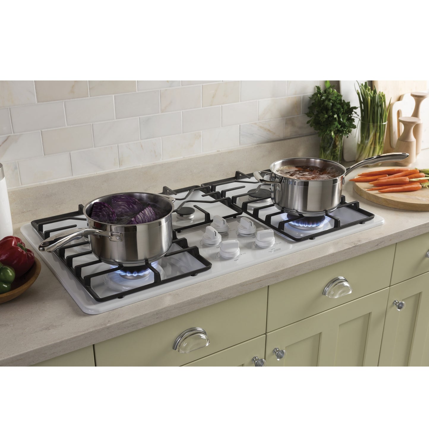 Built-in gas cooktop with four burners and stainless steel pots simmering on a kitchen countertop surface