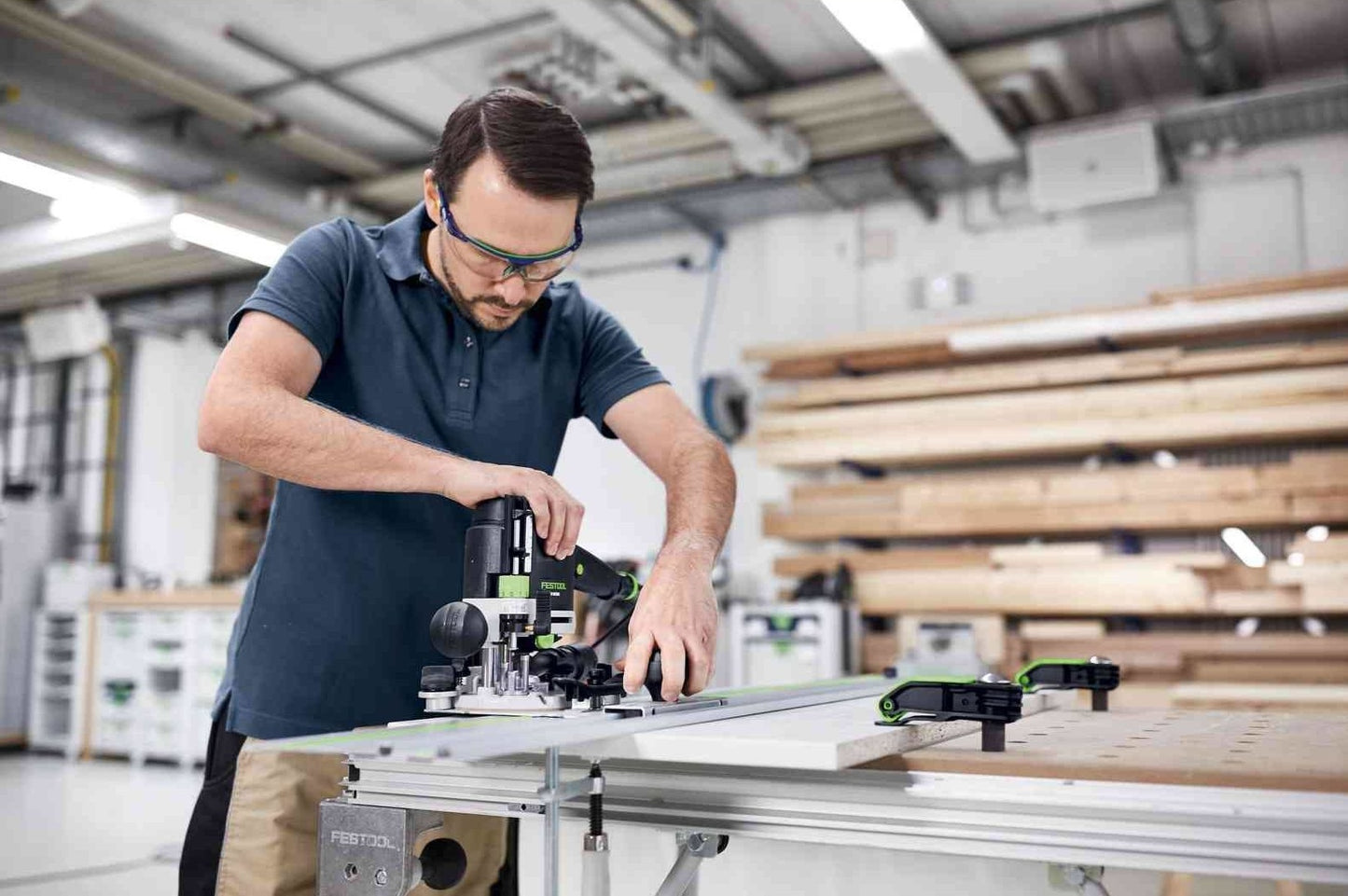 Man using Festool hole drilling set on wood panel in a professional woodworking shop with tools and lumber nearby