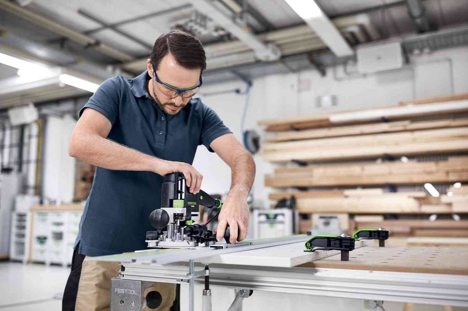 Man using Festool hole drilling set on wood panel in a professional woodworking shop with tools and lumber nearby