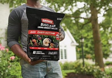 Person holding a black and red bag of Ortho BugClear fast-acting insect killer for outdoor lawn pest control