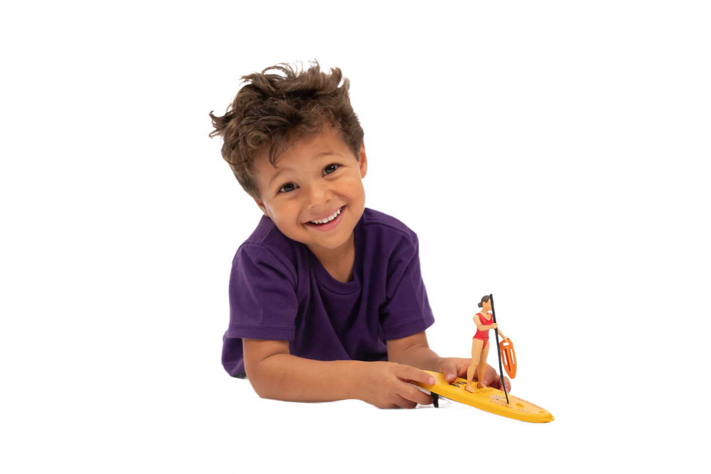 Young child smiling while holding a Bruder lifeguard figure on a yellow stand-up paddleboard toy for playtime fun