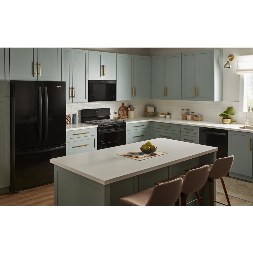 Kitchen with black flush mount microwave above black stove and refrigerator, blue-gray cabinetry, and white countertops in warm light
