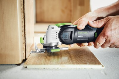 Cordless oscillating power tool cutting wood flooring with ergonomic grip for precise home improvement tasks