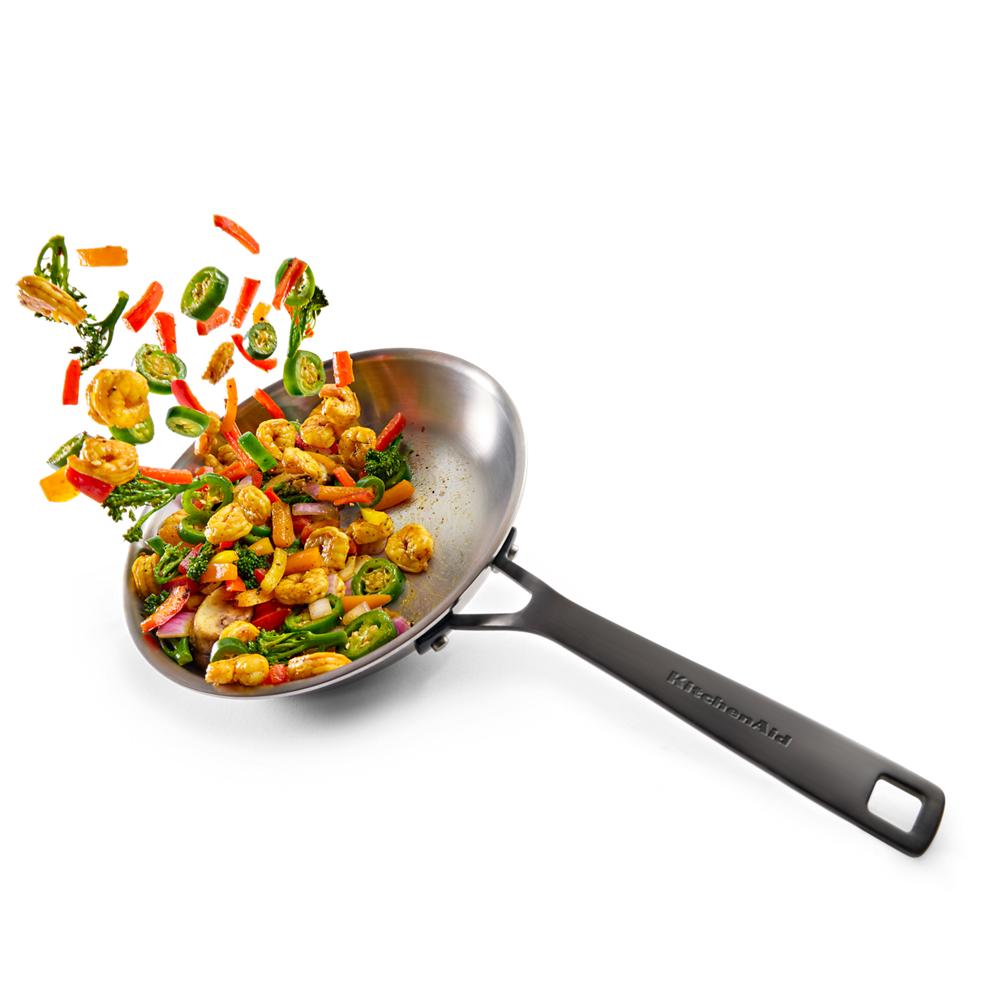 Stainless steel wok with stir-fried shrimp and mixed vegetables mid-toss for kitchenware and home improvement tools