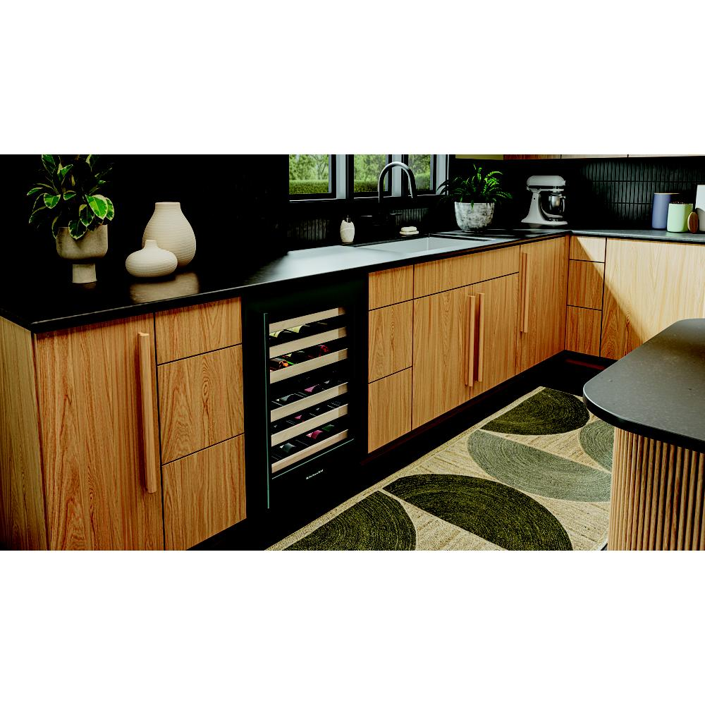 Undercounter wine cellar with wood-front racks storing bottles, integrated into modern kitchen cabinetry with black countertops