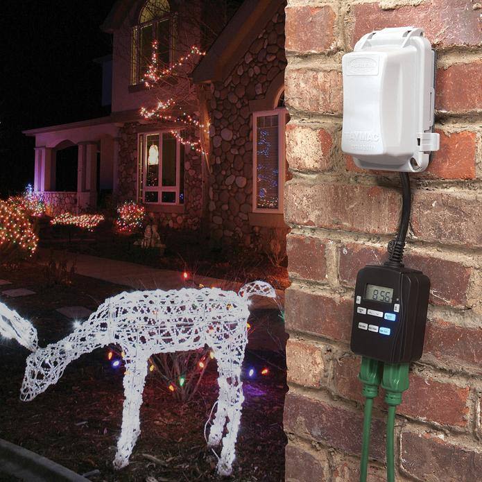 Outdoor digital timer with two outlets mounted on brick wall controlling holiday lights in residential home improvement setting