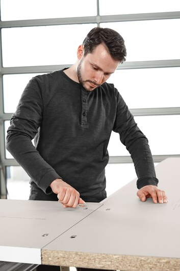 Man marking precise measurements on particle board for woodworking tools and home improvement projects