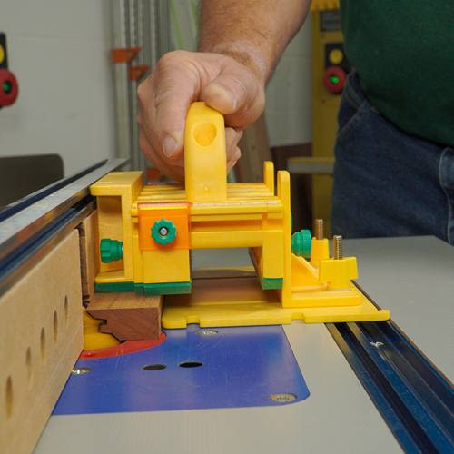 Yellow and green woodworking push block in use for precise control on table saw in tool accessories collection