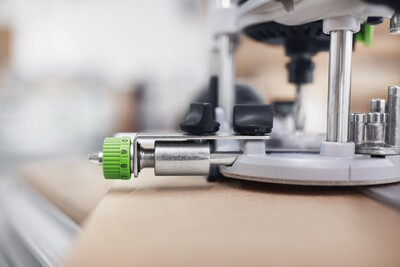 Close-up of fine adjustment guide stop with green numbered dial on a woodworking router for precise tool control in home improvement