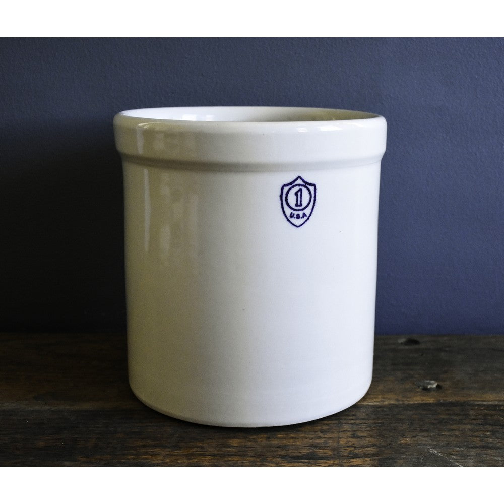 Cream-colored 1-gallon stoneware crock with a small blue shield emblem for home storage or kitchen use