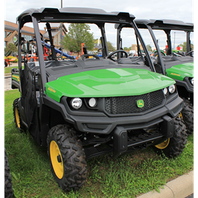 Green full-size John Deere utility vehicle with custom predator terrain tires designed for rugged outdoor use
