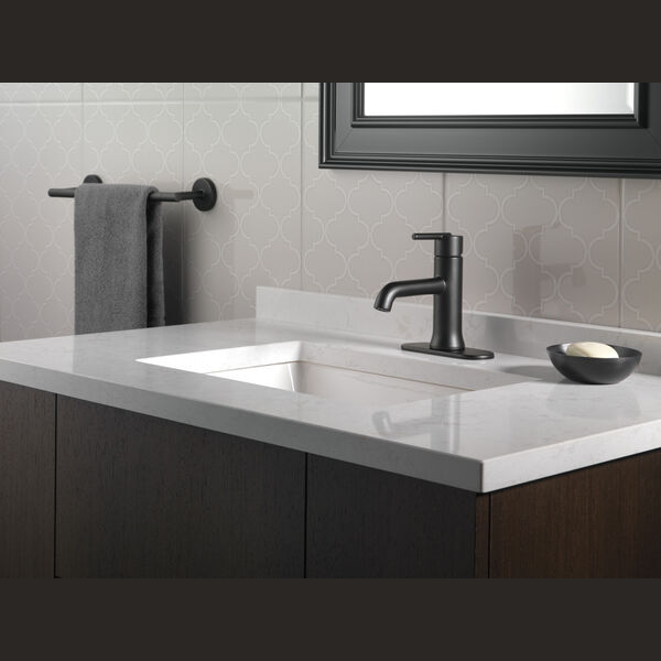 Matte black single handle bathroom faucet installed on white marble countertop with modern minimalist decor
