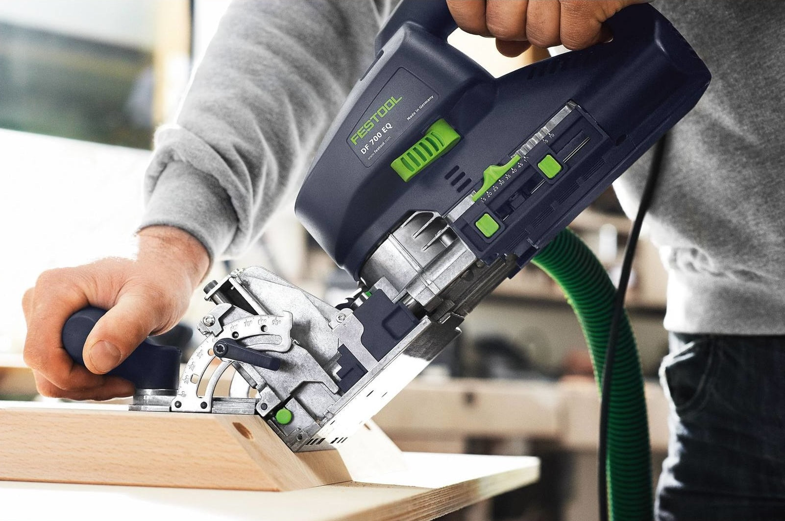 Person using a Festool Domino XL power tool for precise joinery on a wood plank in woodworking tools collection
