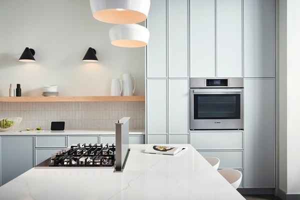 Modern kitchen with built-in stainless steel oven and gas cooktop on white marble island in Bosch appliances collection