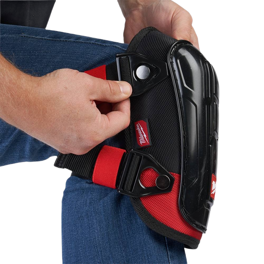 Hand adjusting red and black knee pad with molded protective cap for durable safety in hardware and home improvement tasks