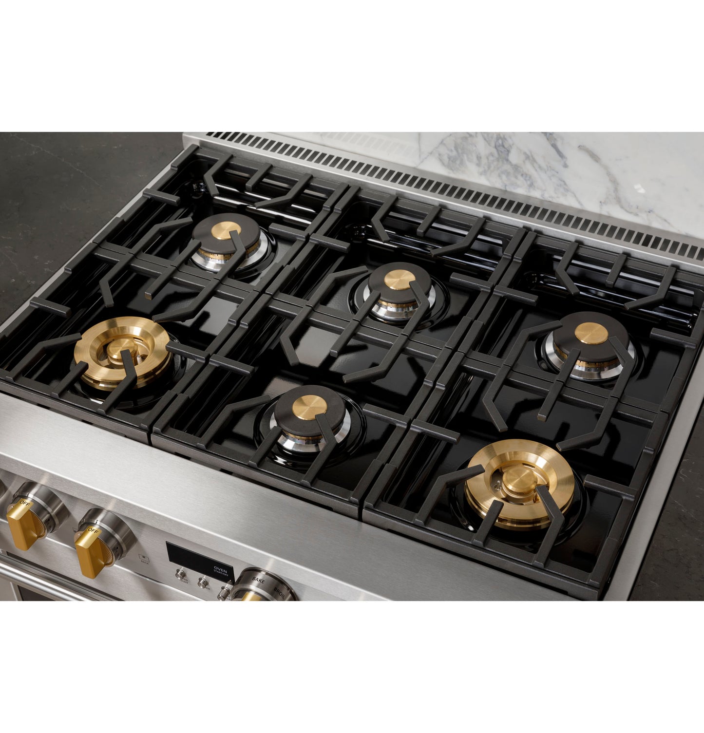Top view of stainless steel dual-fuel range with six burners, featuring brass burner caps and black grates in kitchen appliances collection