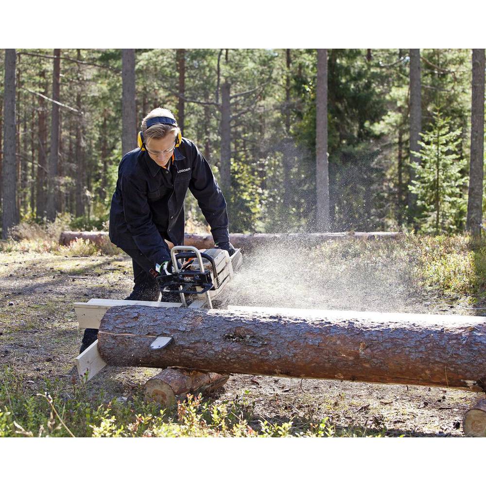 Person using a chainsaw on a large log secured by a portable wood cutting jig in a forest setting