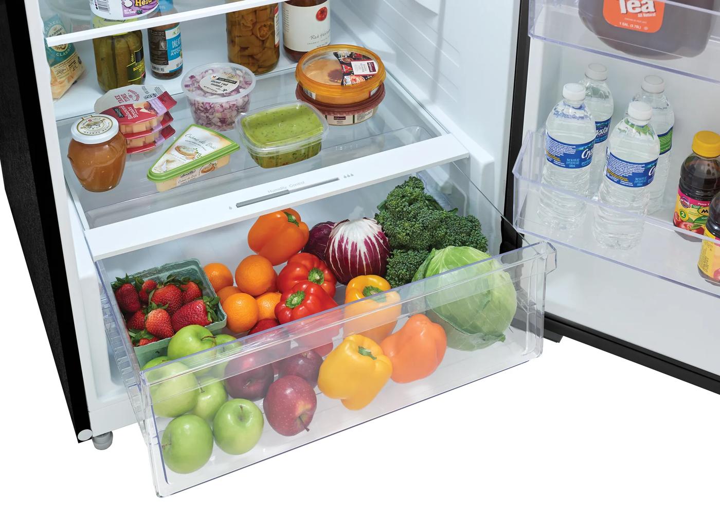 Clear crisper drawer filled with fresh fruits and vegetables inside a top freezer refrigerator in Appliances collections