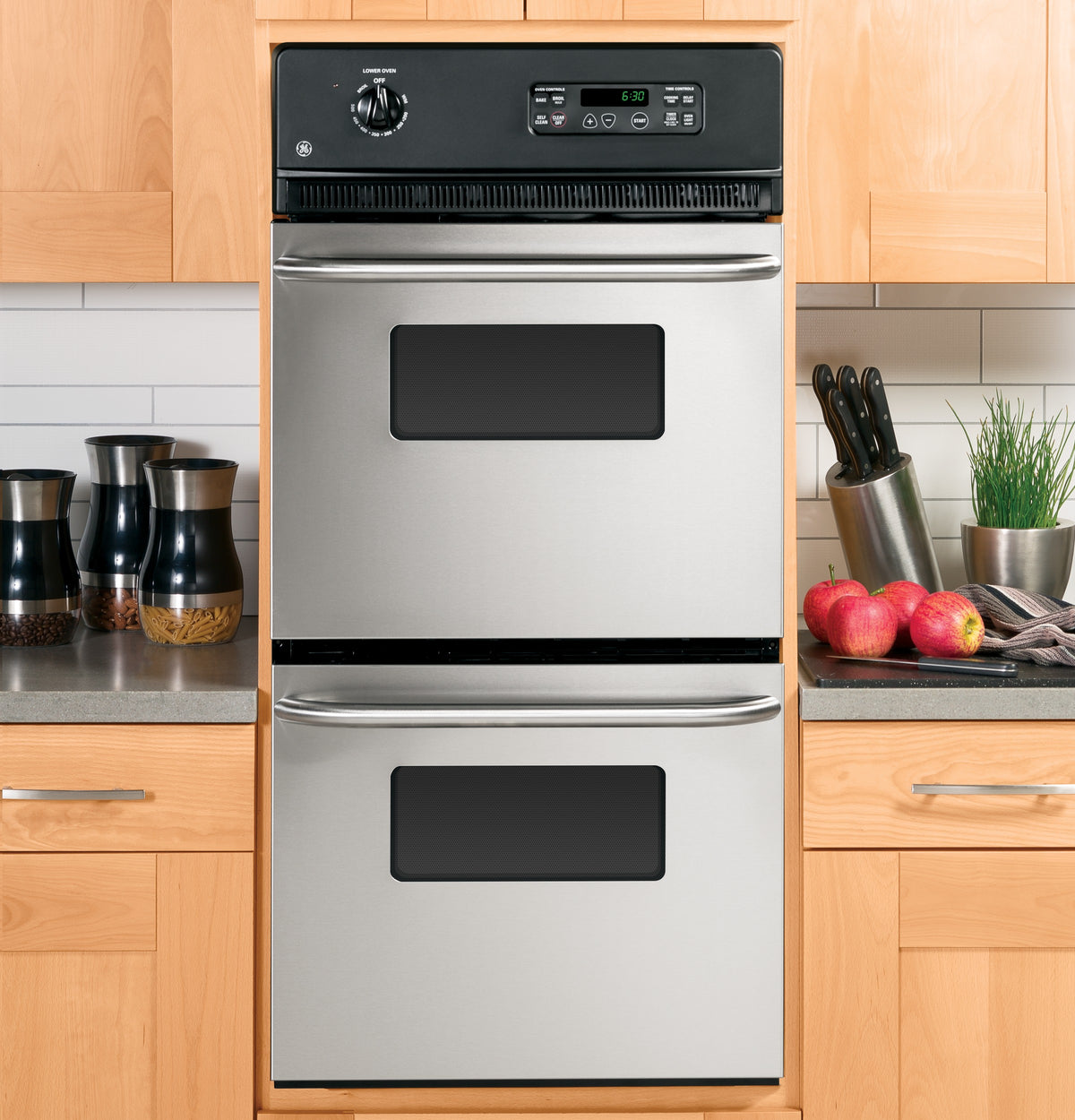 Built-in stainless steel double wall oven with digital controls integrated into light wood kitchen cabinetry in Appliances collection