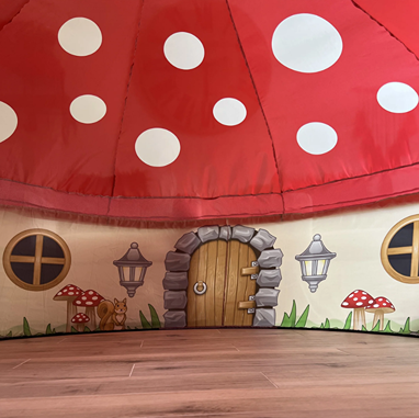 Children's indoor play tent designed to look like a mushroom house with wood floor and whimsical details
