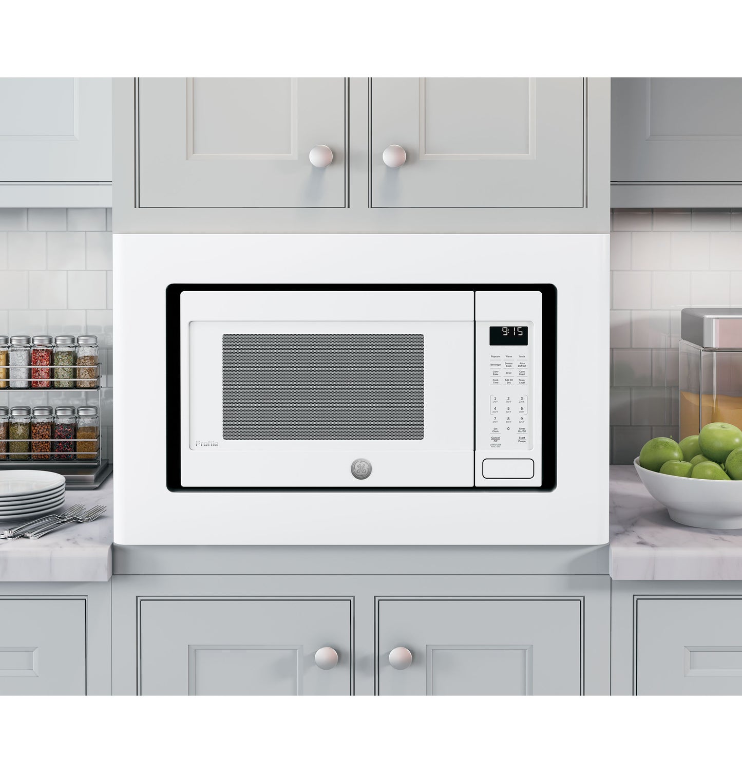 White built-in trim kit framing a microwave in a modern kitchen with gray cabinets and marble countertops