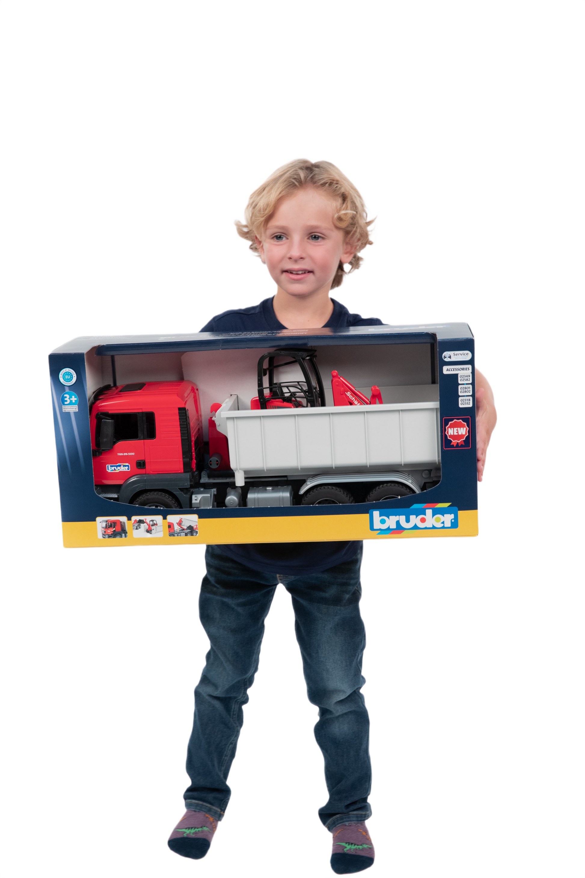 Child holding boxed red toy truck with detachable container and compact loader for realistic play and construction use