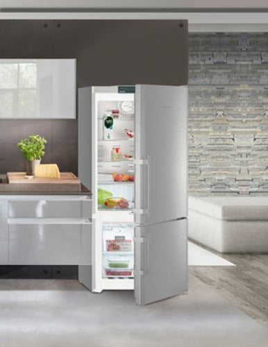 Open stainless steel fridge-freezer showing organized shelves with fresh food in modern kitchen setting