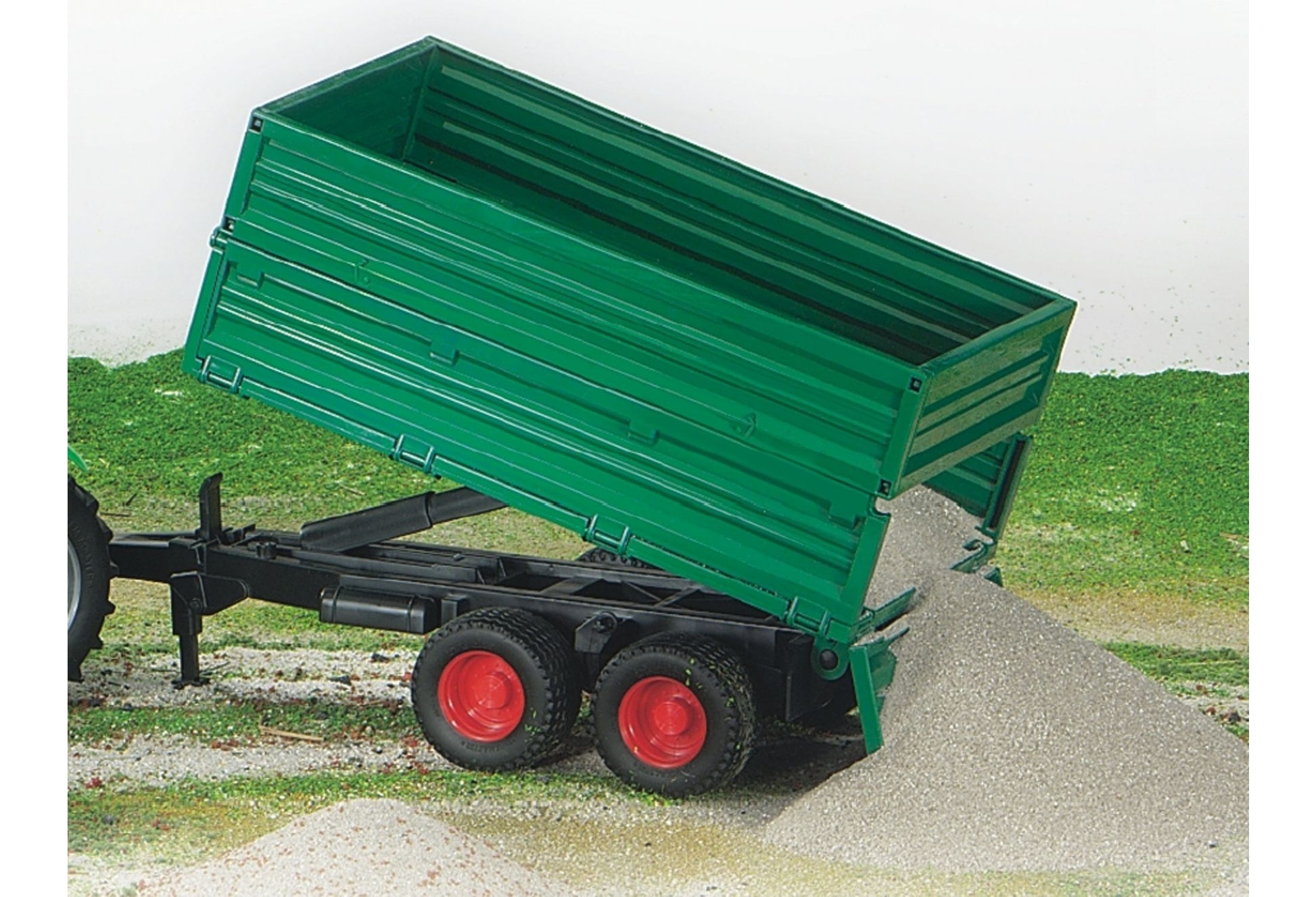 Green tandem axle tipping trailer with red wheels unloading gravel from removable top in Bruder Toys collection