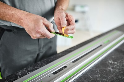 Hands applying adhesive pad to aluminum guide rail for woodworking tool accessories and home improvement under $50 collections